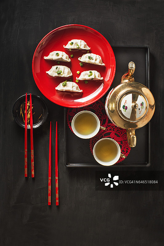 黑色质朴的桌面上放着饺子和茶具。图片素材