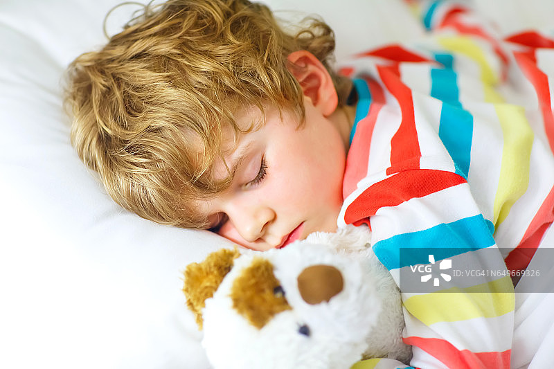 金发小男孩穿着五颜六色的睡衣睡觉图片素材