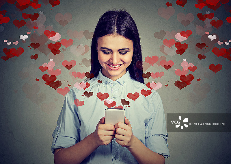 美丽幸福的女人在手机上发爱情短信图片素材