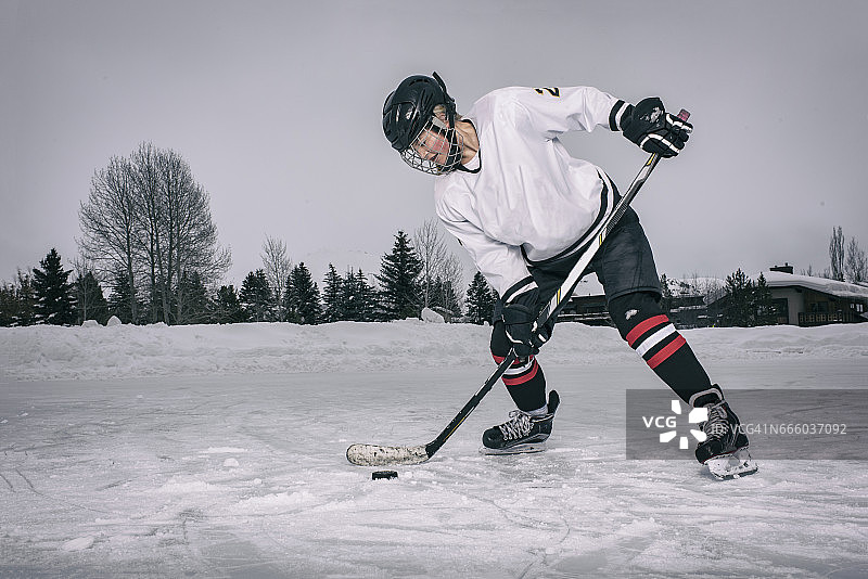十几岁的女孩冰上曲棍球运动员在冬天在室外溜冰场上击球图片素材