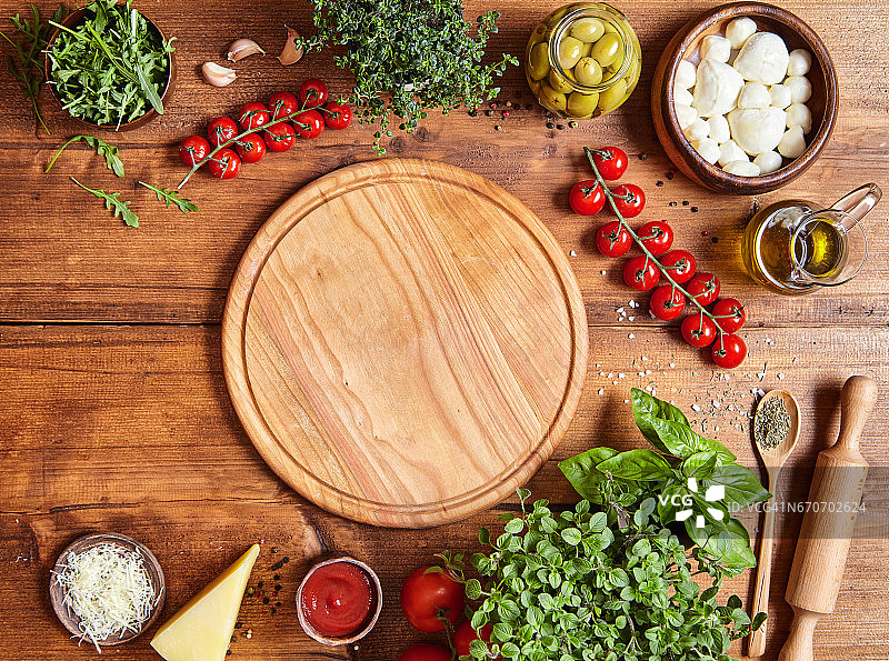 切木板与传统的披萨配料:马苏里拉奶酪，番茄酱，罗勒，橄榄油，奶酪，香料。图片素材