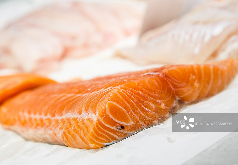 新鲜生三文鱼鱼片陈列于海鲜市场。图片素材