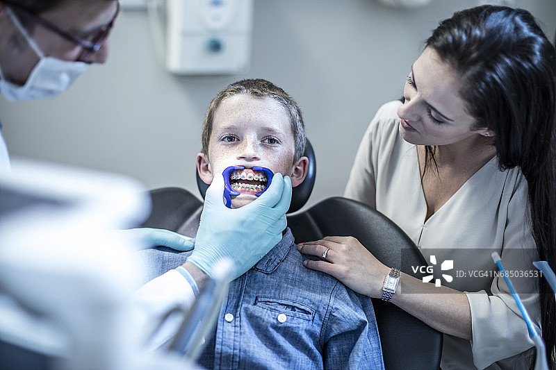 男孩与母亲在牙科手术接受正畸治疗图片素材