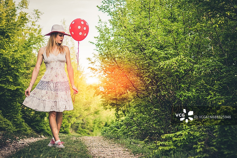 森林里戴着帽子拿着气球的年轻女子图片素材