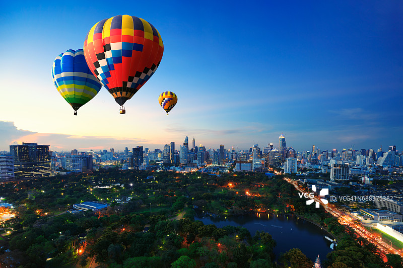 热气球在夕阳的背景下飞过城市图片素材