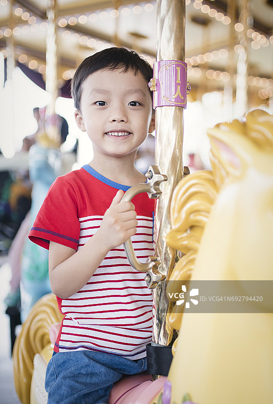 孩子在一个多彩的嘉年华旋转木马上玩得很开心图片素材