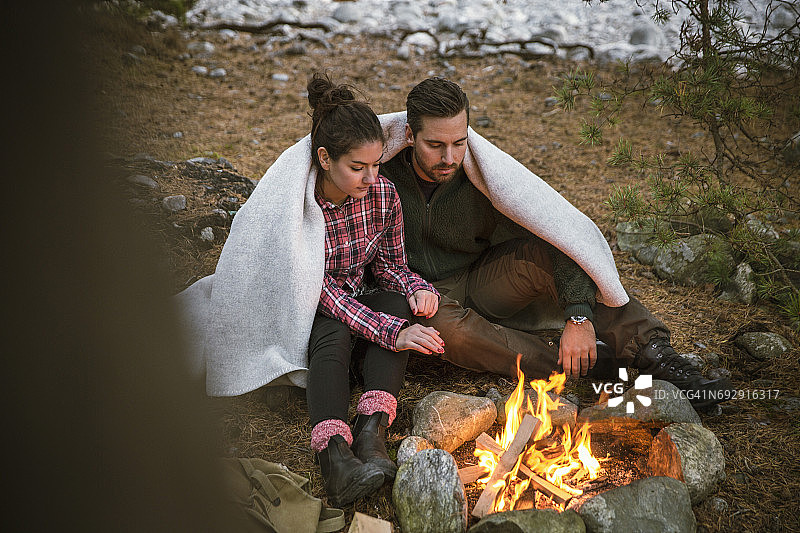 一对夫妇裹着毯子，坐在营地的火坑旁图片素材