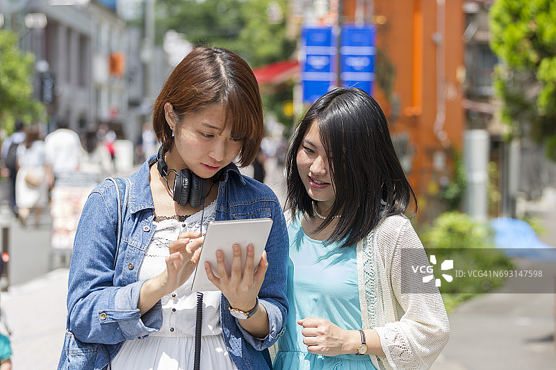 日本年轻女性在街上用平板电脑搜索图片素材