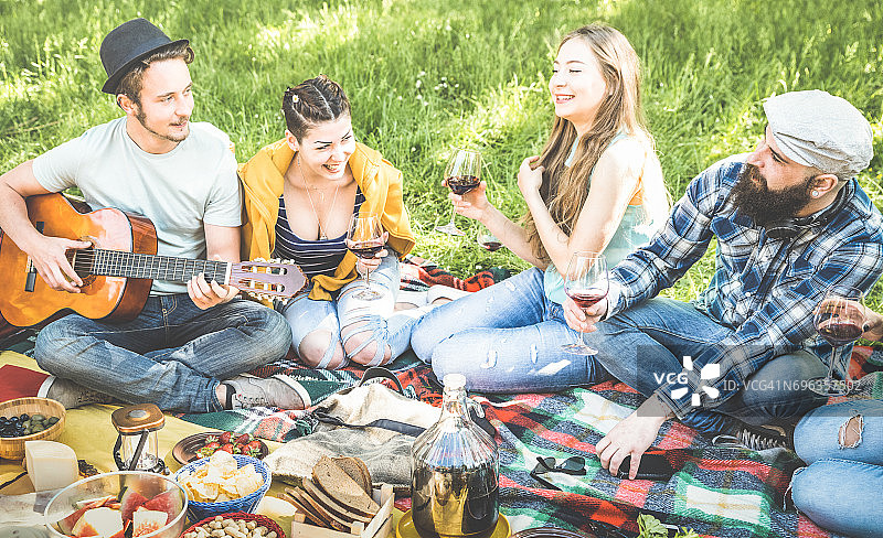 朋友群有乐趣的户外欢呼在烧烤野餐与古董吉他-年轻人享受夏天一起在烧烤花园派对-青年友谊概念-聚焦胡子嬉皮士的家伙图片素材