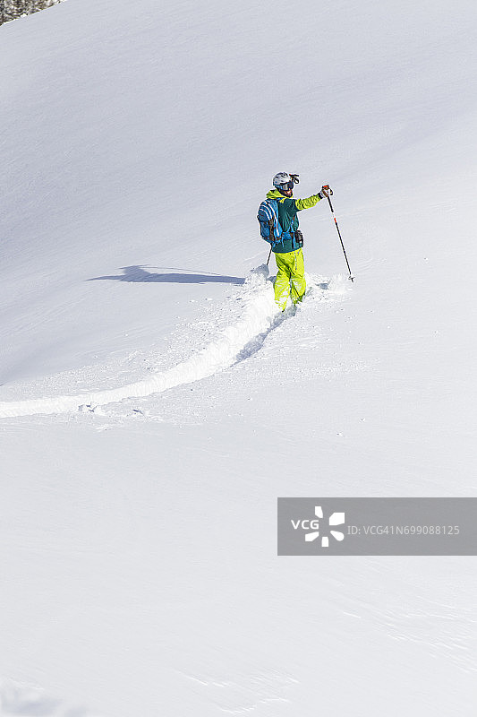 快乐的滑雪者在新雪中创造第一个轨迹图片素材