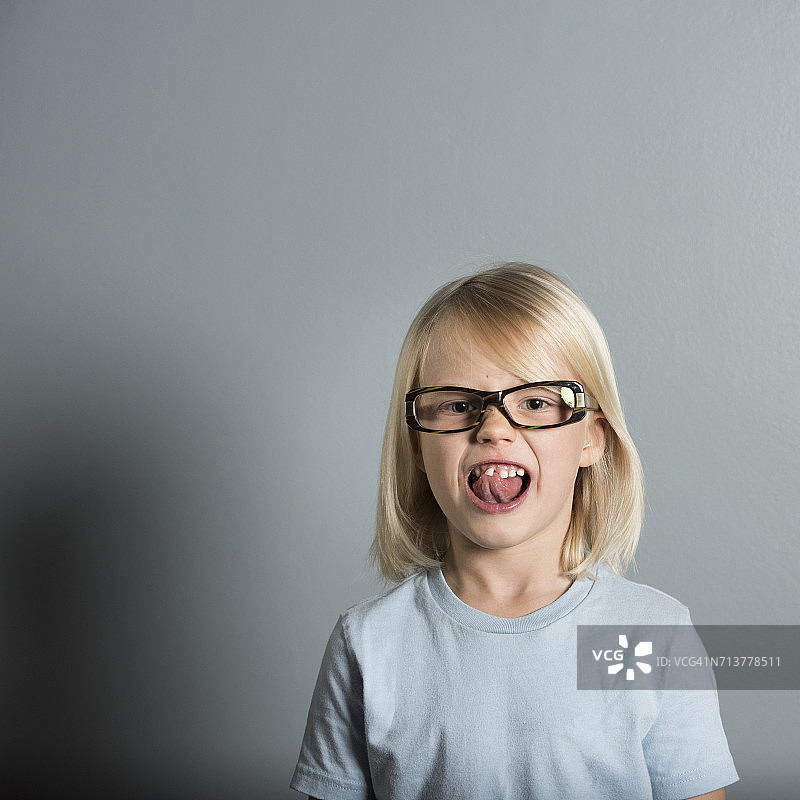 一个戴眼镜的男孩伸出舌头的肖像图片素材