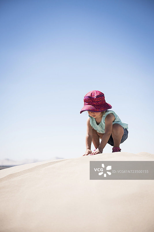 美国犹他州的小撒哈拉沙漠，一名女婴蹲在沙丘上图片素材