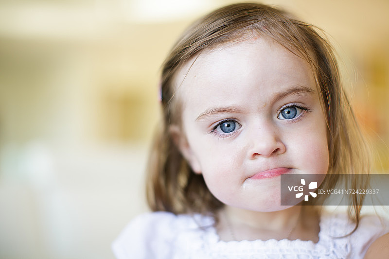 蓝眼睛小女孩咬嘴唇的肖像图片素材