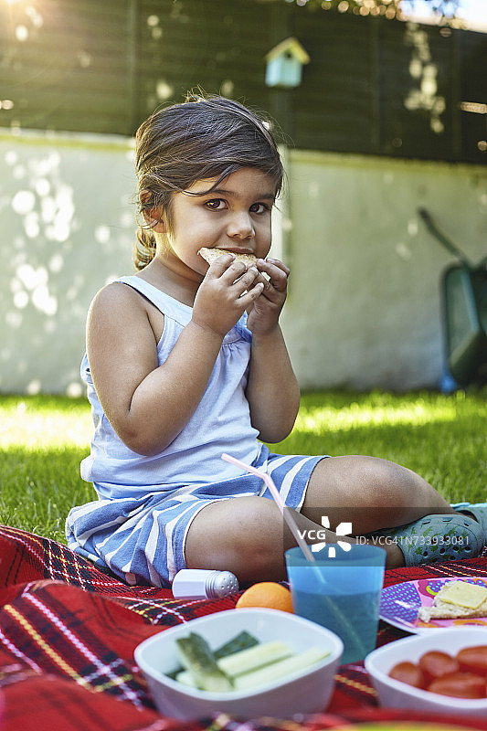 年轻女孩的肖像野餐在花园，吃三明治图片素材