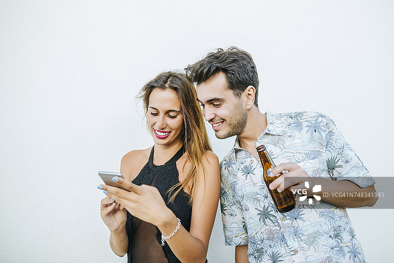 年轻夫妇在户外拿着啤酒和手机图片素材