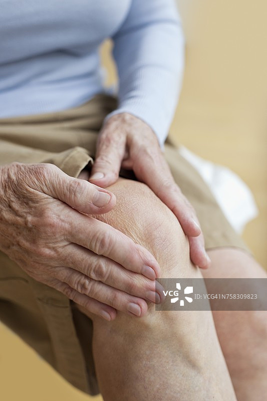 老妇人抱着酸痛的膝盖图片素材