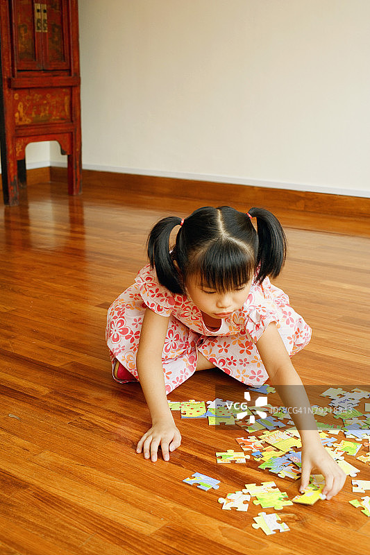 一个女孩坐在地板上玩拼图游戏的特写镜头图片素材