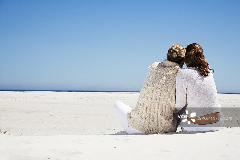母亲和女儿坐在海滩上，后视镜图片素材