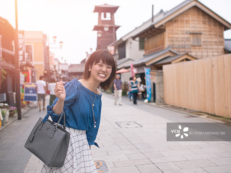 快乐的年轻女子访问一个古老的日本城镇图片素材