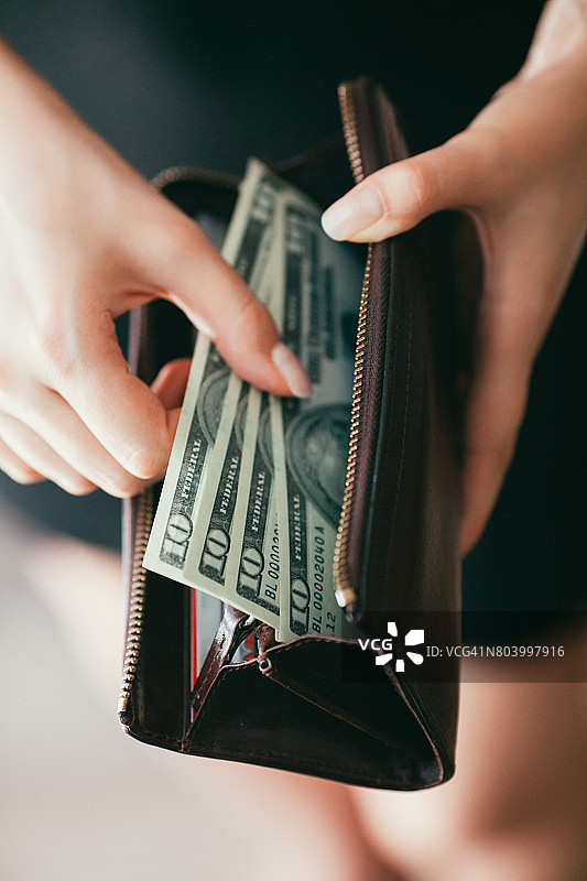 一个女人正在从钱包里取出钱图片素材