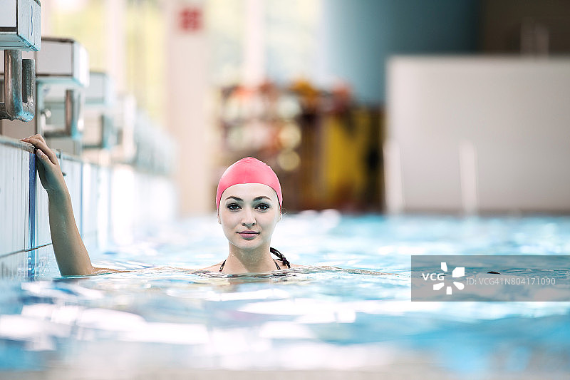 美丽的女子帽子微笑着看着镜头在游泳池的边界图片素材