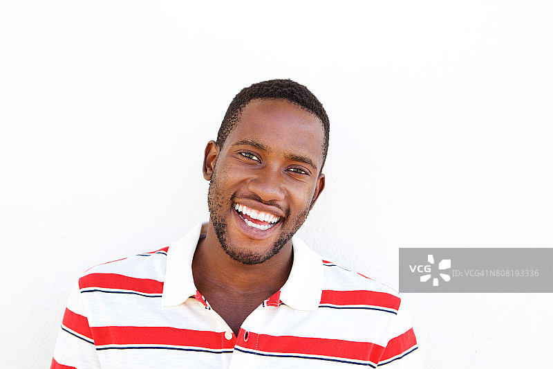 年轻的非裔美国人对着白墙微笑图片素材