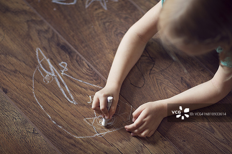孩子用蜡笔在硬木地板上画画图片素材