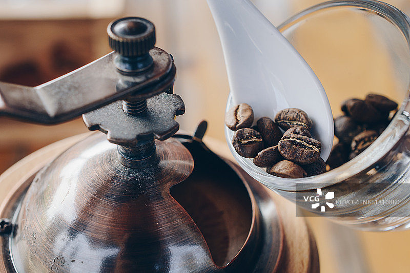 咖啡师准备好咖啡豆放入咖啡研磨机研磨咖啡豆。图片素材