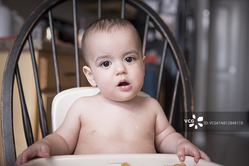 12个月大的异卵双胞胎男婴在高椅上严肃地凝视着图片素材