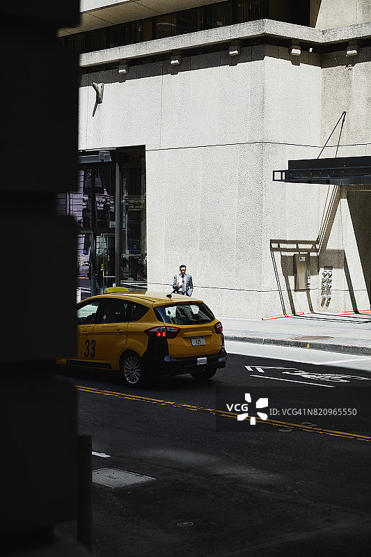 商人一边在城市人行道上等待汽车，一边用智能手机工作图片素材