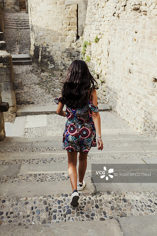 后视图年轻游客走在一个意大利村庄图片素材