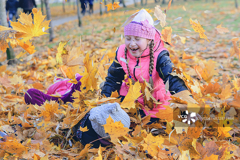 孩子们在秋天公园玩。树上的落叶。图片素材
