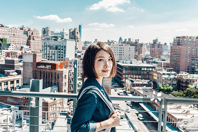 年轻的办公室女士在屋顶上眺望纽约的城市风景图片素材