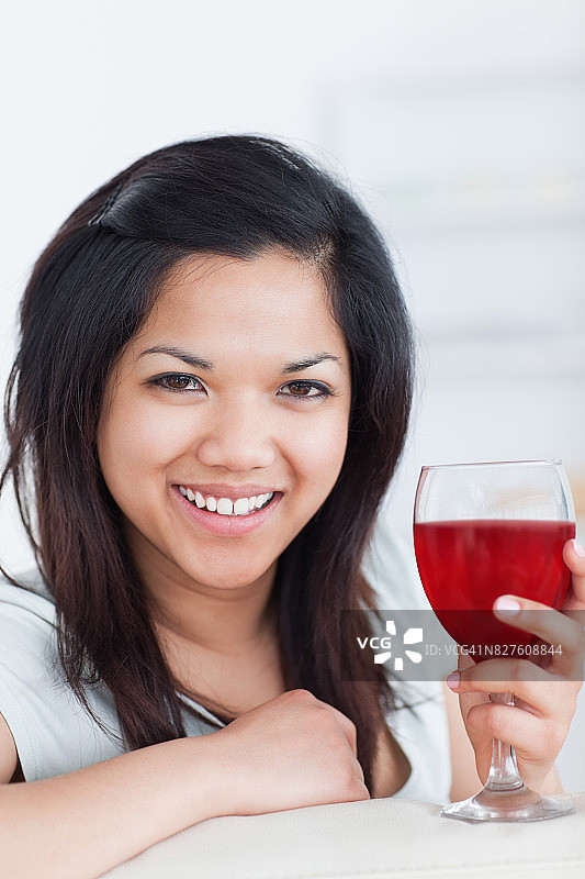 一个微笑的女人拿着一杯红酒的特写图片素材