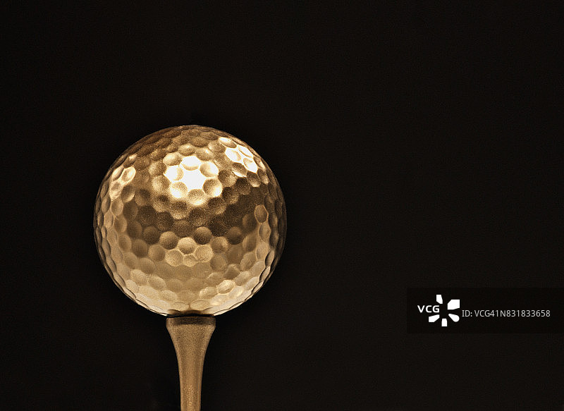 黑色背景上的金色高尔夫球图片素材