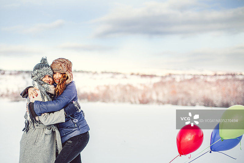 两个微笑的女孩在冬天拿着气球图片素材
