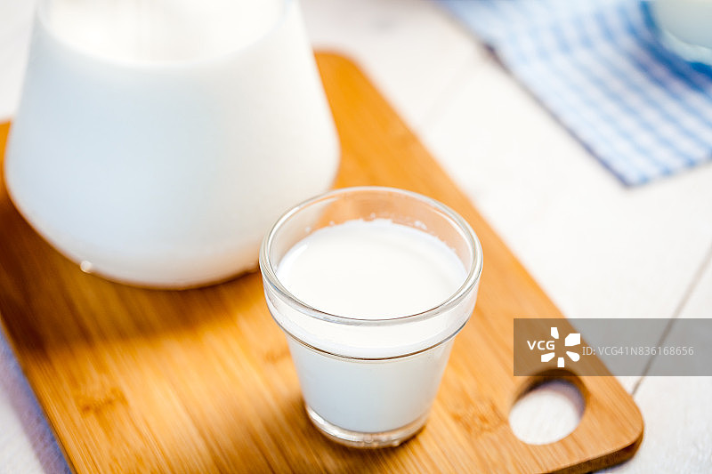 牛奶和几杯牛奶放在一张质朴的木头桌子上。图片素材