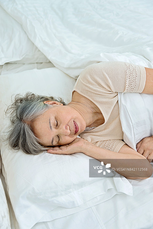 老妇人躺在床上睡觉图片素材