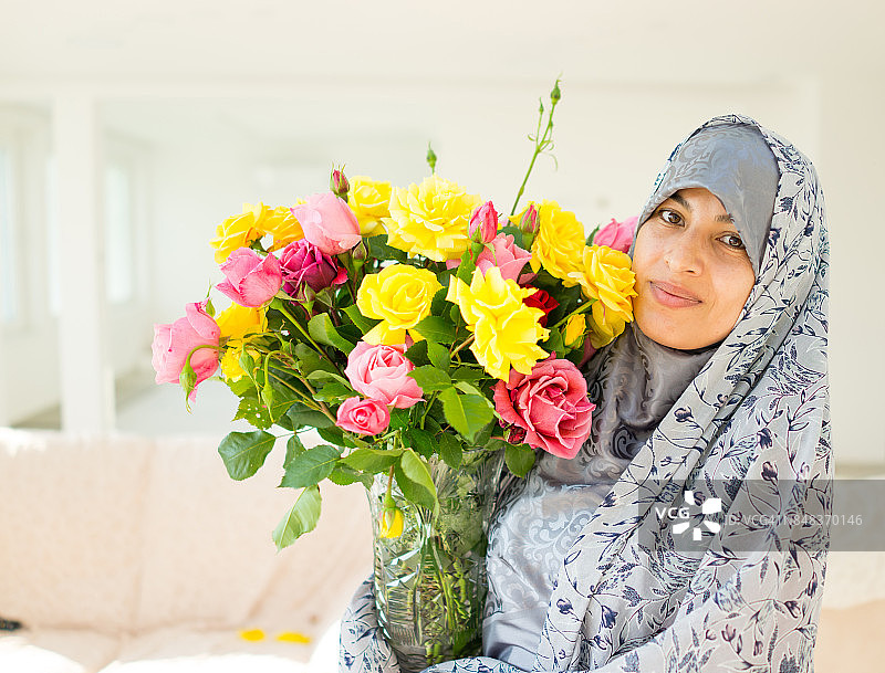 穆斯林妇女在家里拿着鲜花图片素材