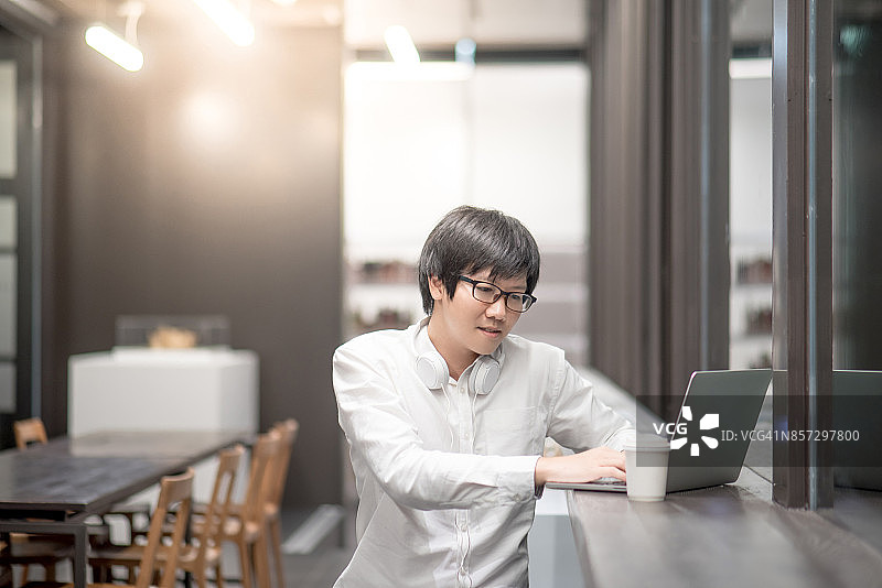 年轻的亚洲人在咖啡店用笔记本电脑工作图片素材