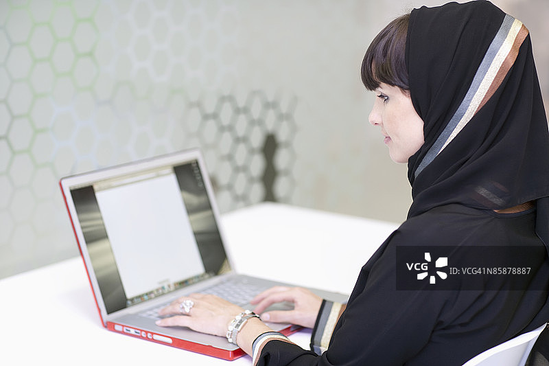 阿拉伯妇女在办公室使用笔记本电脑。图片素材