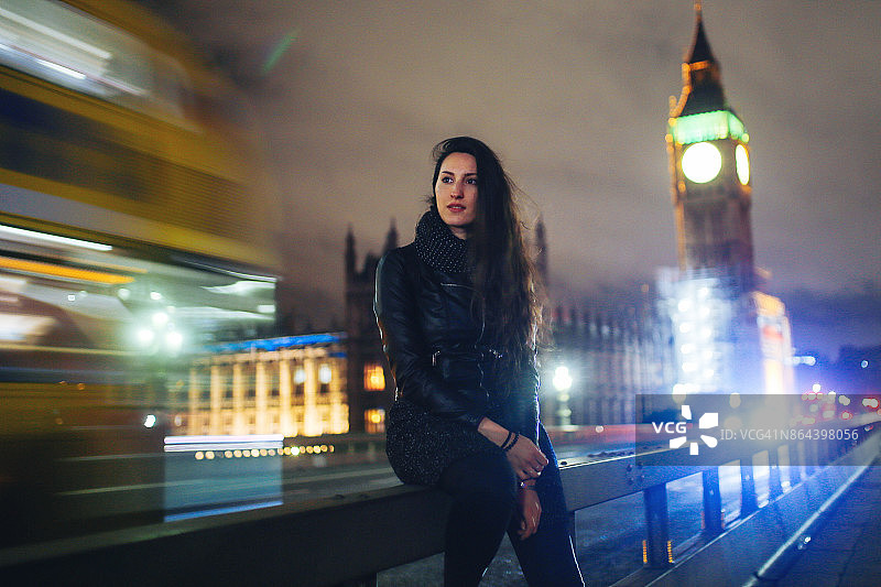 一个年轻女子晚上在伦敦等出租车图片素材