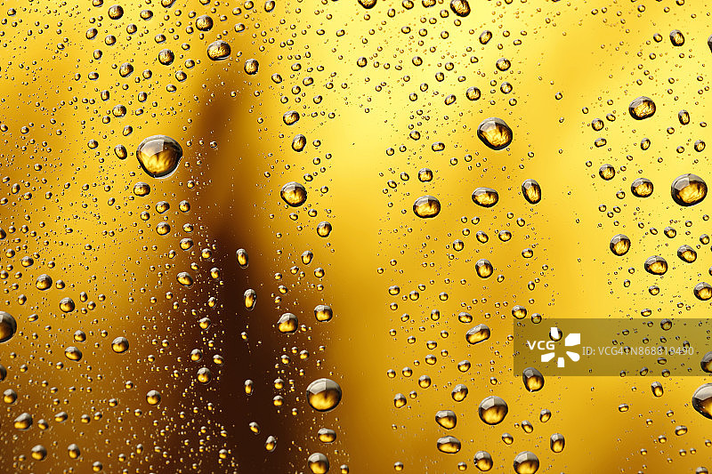 冰冷的玻璃覆盖着水滴凝结冷饮水滴金色的黄色-橙色的饮料背景雨点纹理近图片素材
