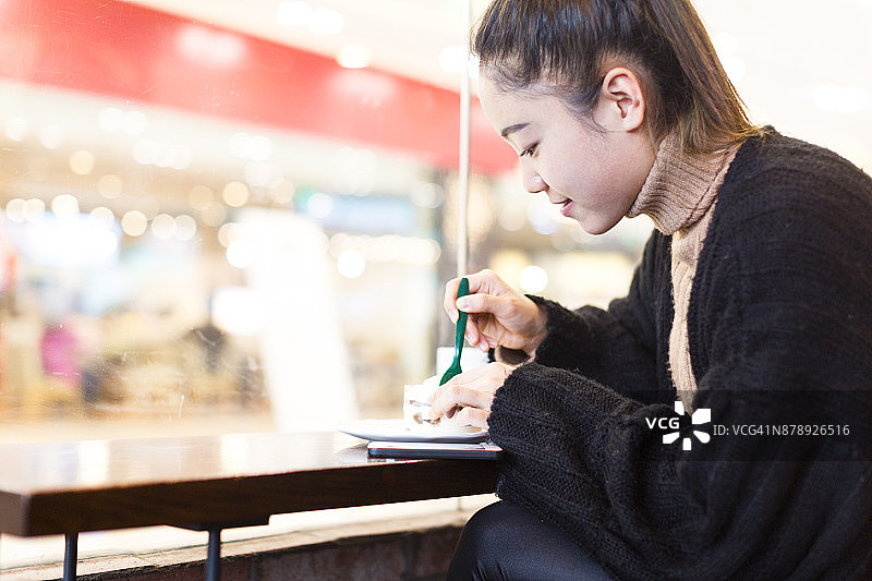 一个女人正在咖啡馆里喝着咖啡吃着糖果，手里拿着手机图片素材