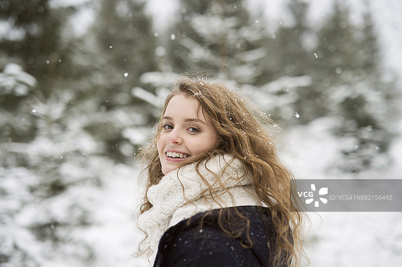冬日森林里微笑的年轻女子的肖像图片素材