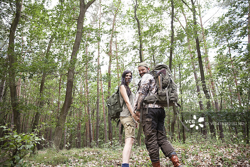 一对背着背包在森林里徒步旅行的幸福夫妇图片素材