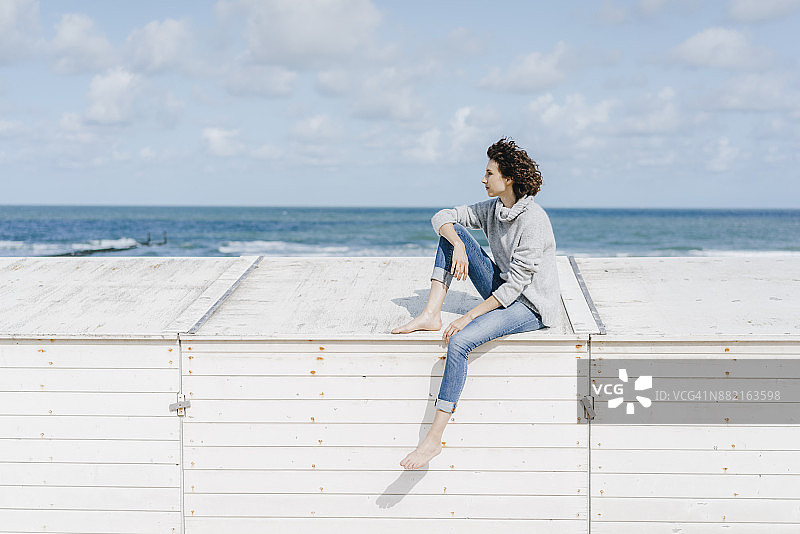 一个女人坐在沙滩上的木箱上图片素材