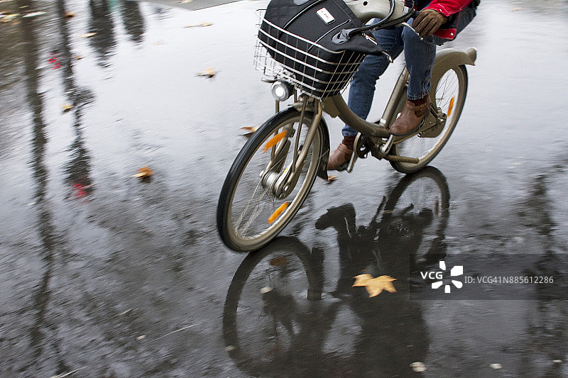 法国，巴黎，一个骑自行车的人在雨中。图片素材