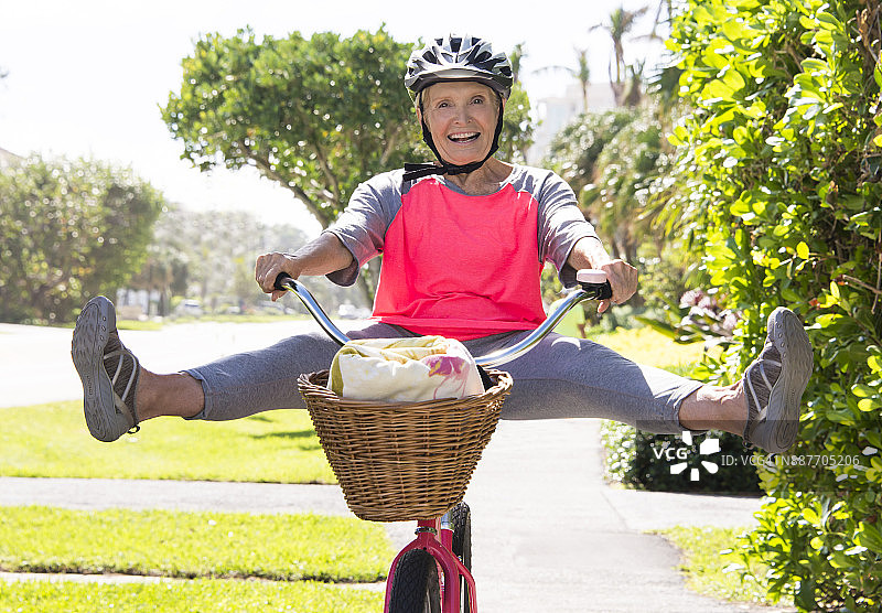 快乐健康的老年妇女在自行车上玩。图片素材