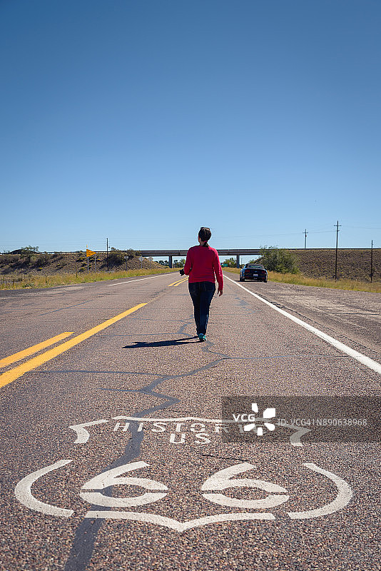 一个女人走在遥远的沙漠路上图片素材